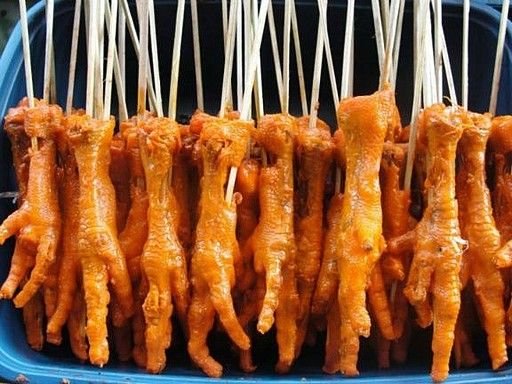 The image shows Adidas, a popular Filipino street food made from skewered and grilled chicken feet. The chicken feet are marinated and cooked until tender, offering a savory snack that is enjoyed by many.