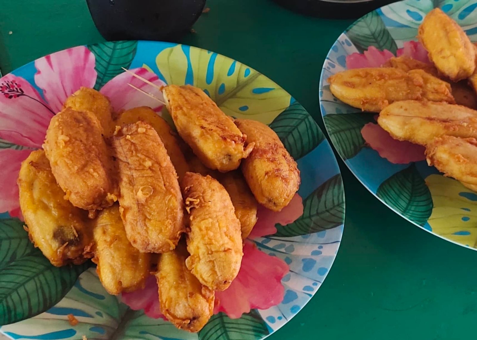 A plate of freshly fried badoya, a traditional Filipino snack made from bananas coated in a crispy batter, displayed on a colorful floral plate, perfect for an authentic Badoya recipe.