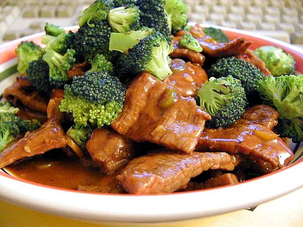 A plate of Beef Pochero with tender beef slices and broccoli.