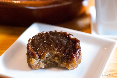 A piece of Bibingkang Kanin, a Filipino rice cake, served on a small white plate. The rice cake has a glossy caramelized top layer, with a chewy, sticky texture that is rich and sweet, highlighting the traditional flavors of this beloved Filipino dessert.