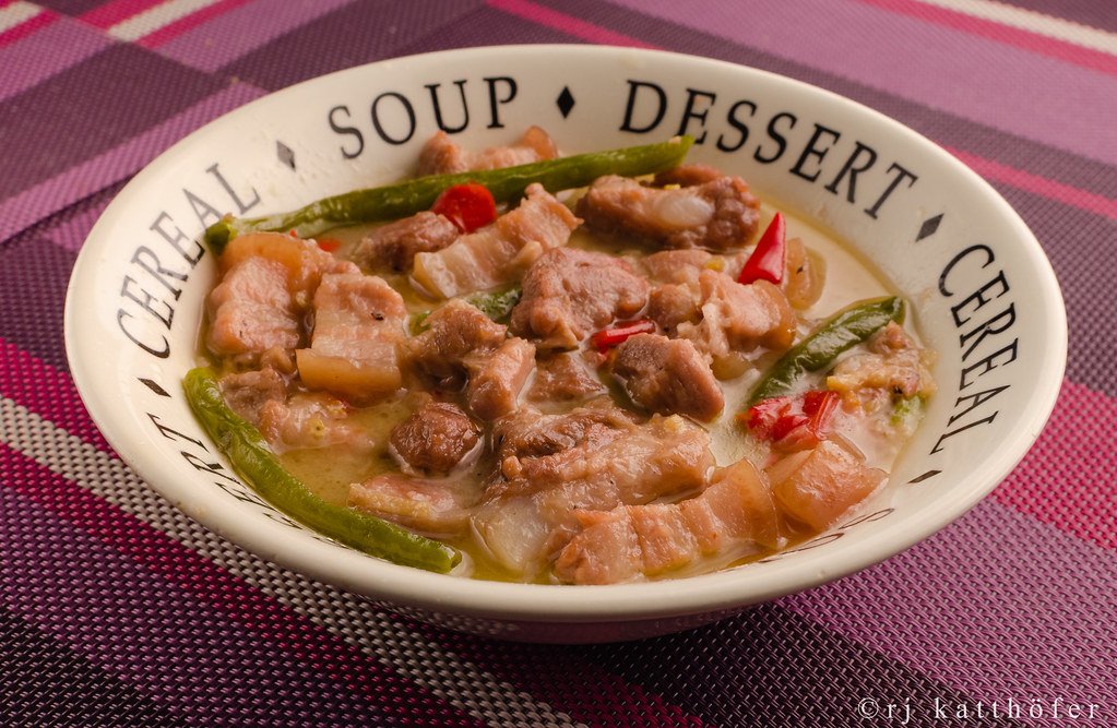 Close-up of a hearty serving of Bicol Express, featuring tender pork in a creamy coconut-based sauce with green chilies, served in a soup bowl.