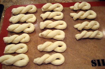 Uncooked Caramelized Pilipit dough twists arranged neatly on a baking mat. The dough is intricately twisted into its signature spiral shape, ready to be fried and caramelized into a crispy, sweet Filipino snack.