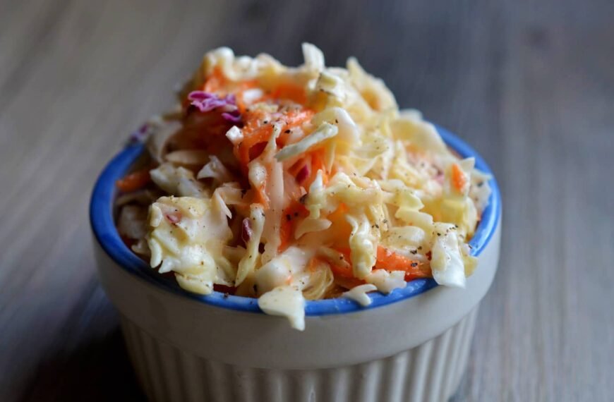 A bowl of fresh coleslaw with shredded cabbage and carrots.
