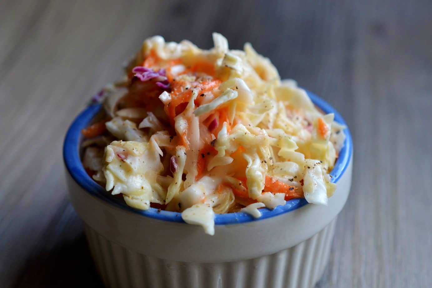 A bowl of fresh coleslaw with shredded cabbage and carrots.