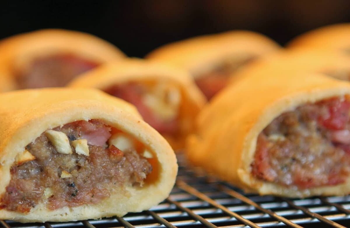 Crispy apple rolls with a golden crust and sweet filling on a cooling rack.