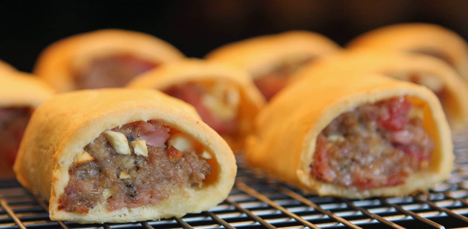 Crispy apple rolls with a golden crust and sweet filling on a cooling rack.