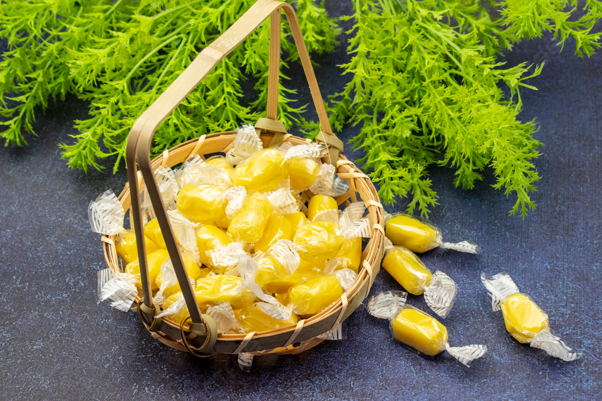 A woven basket filled with individually wrapped Durian candies, featuring their signature yellow color. This Durian Candy Recipe showcases the sweet and creamy delicacies, a popular treat in many Asian countries, made from the famously aromatic durian fruit.