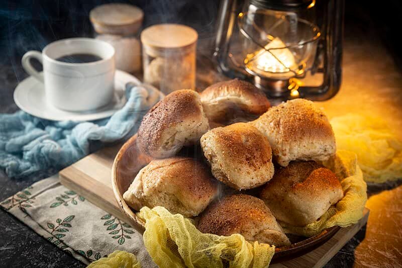 A cozy scene featuring a plate of warm, freshly baked pandesal rolls paired with a cup of coffee, perfect for breakfast, showcasing the Easy Pandesal Recipe.