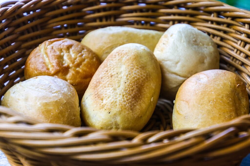 A basket of freshly baked golden-brown pandesal rolls, a popular Filipino bread, perfect for breakfast or snacks in the Easy Pandesal Recipe.