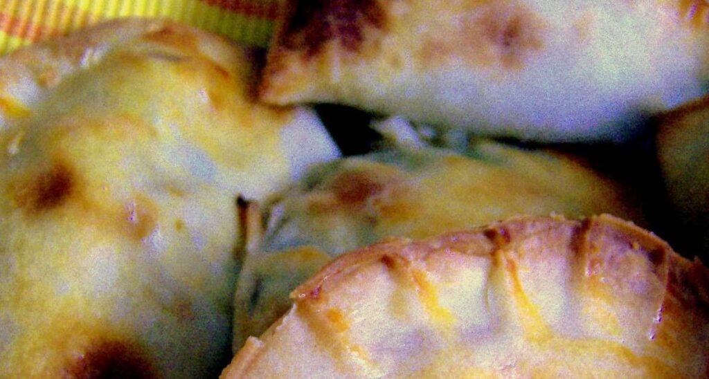 Close-up of freshly baked Empanaditas, small Filipino hand pies with a golden-brown crust. These pastries have a flaky exterior and are filled with a savory mixture, making them a delicious snack or appetizer.