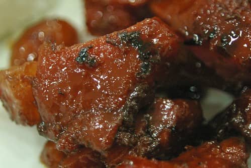 Close-up of homemade tocino, a Filipino cured pork dish, showing its caramelized edges and rich red-brown glaze from marination and cooking. The glossy texture highlights the sweetness and savory flavors of the dish, often enjoyed for breakfast. This image showcases a negosyo (business) recipe, perfect for selling, with included costing information to help aspiring entrepreneurs plan for profitability.