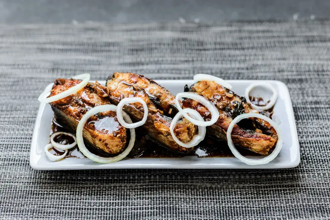 Delicious Bangus Steak Recipe served on a plate, topped with caramelized onions and a savory soy-based sauce.