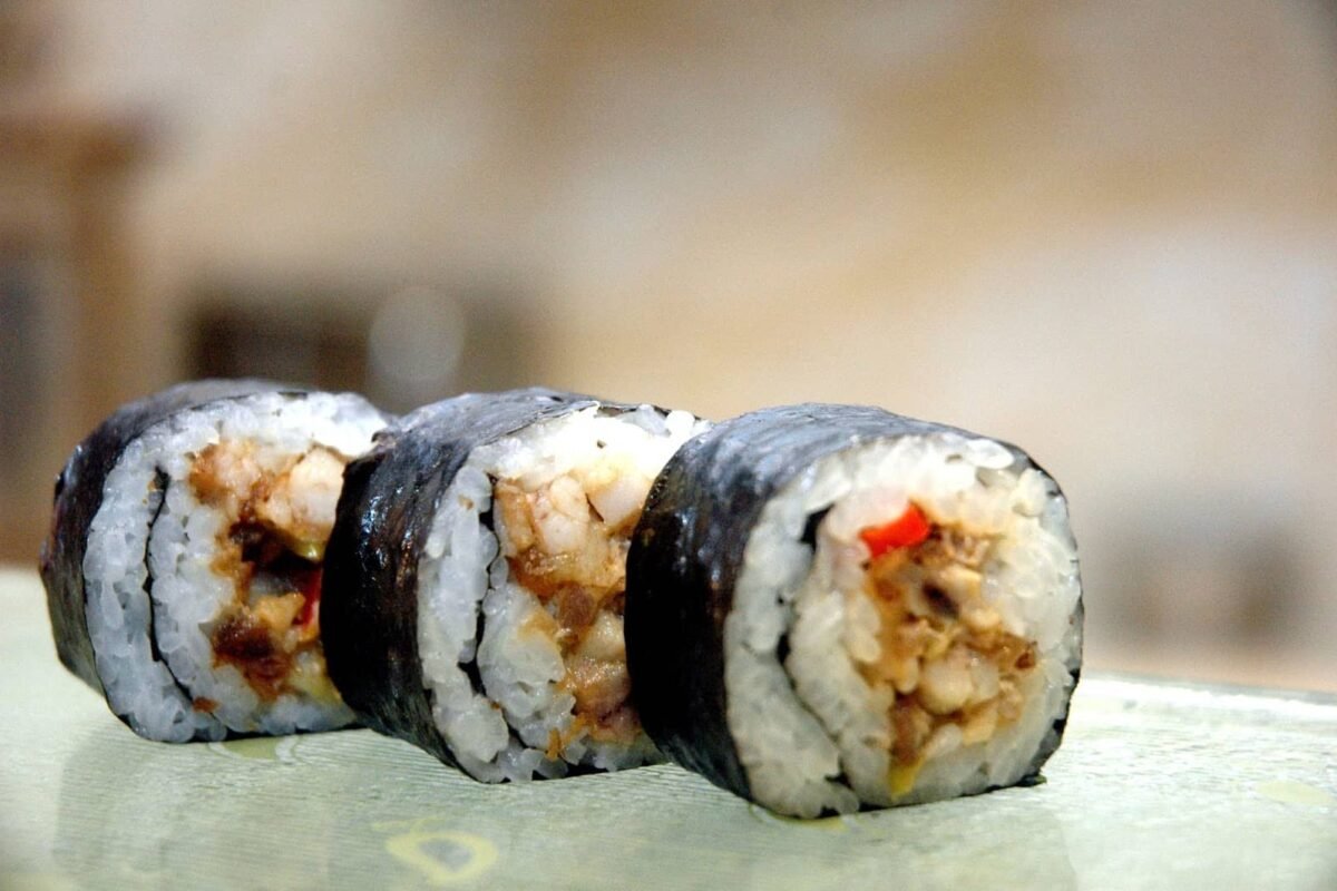 Three pieces of Pinoy-Style Maki, featuring sushi rice wrapped in a layer of nori seaweed, filled with a flavorful mixture of cooked seafood and vegetables. The maki rolls are neatly arranged, showcasing the fusion of traditional Japanese sushi with Filipino flavors.