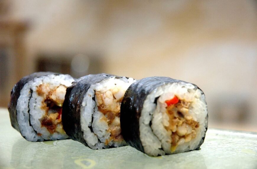 Three pieces of Pinoy-Style Maki, featuring sushi rice wrapped in a layer of nori seaweed, filled with a flavorful mixture of cooked seafood and vegetables. The maki rolls are neatly arranged, showcasing the fusion of traditional Japanese sushi with Filipino flavors.