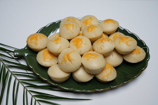 A plate of soft and fluffy puto flan, topped with melted cheese, arranged neatly on a green leaf-shaped dish, showcasing the light and airy texture of this popular Filipino treat.