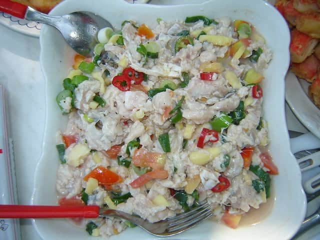 The image depicts Kinilaw na Tuna, a popular Filipino dish made from fresh, raw tuna marinated in vinegar or citrus juice, usually with a combination of ingredients such as onions, ginger, chili peppers, tomatoes, and green onions.