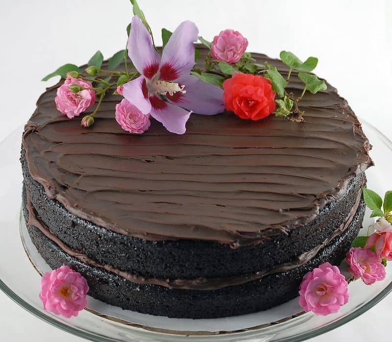 A rich chocolate cake decorated with fresh flowers on top.