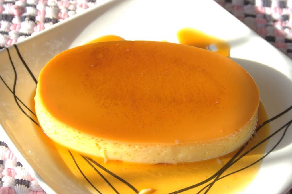 A perfectly cooked leche suman dessert, featuring a smooth custard base topped with rich caramel syrup, served on a white plate, ideal for showcasing an authentic Leche Suman recipe.