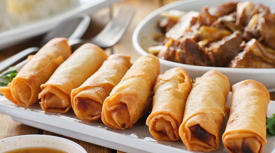 A close-up of golden, crispy Lumpiang Togue rolls arranged neatly on a serving plate. This Lumpiang Togue Recipe features crunchy bean sprout-filled spring rolls perfect for any occasion.