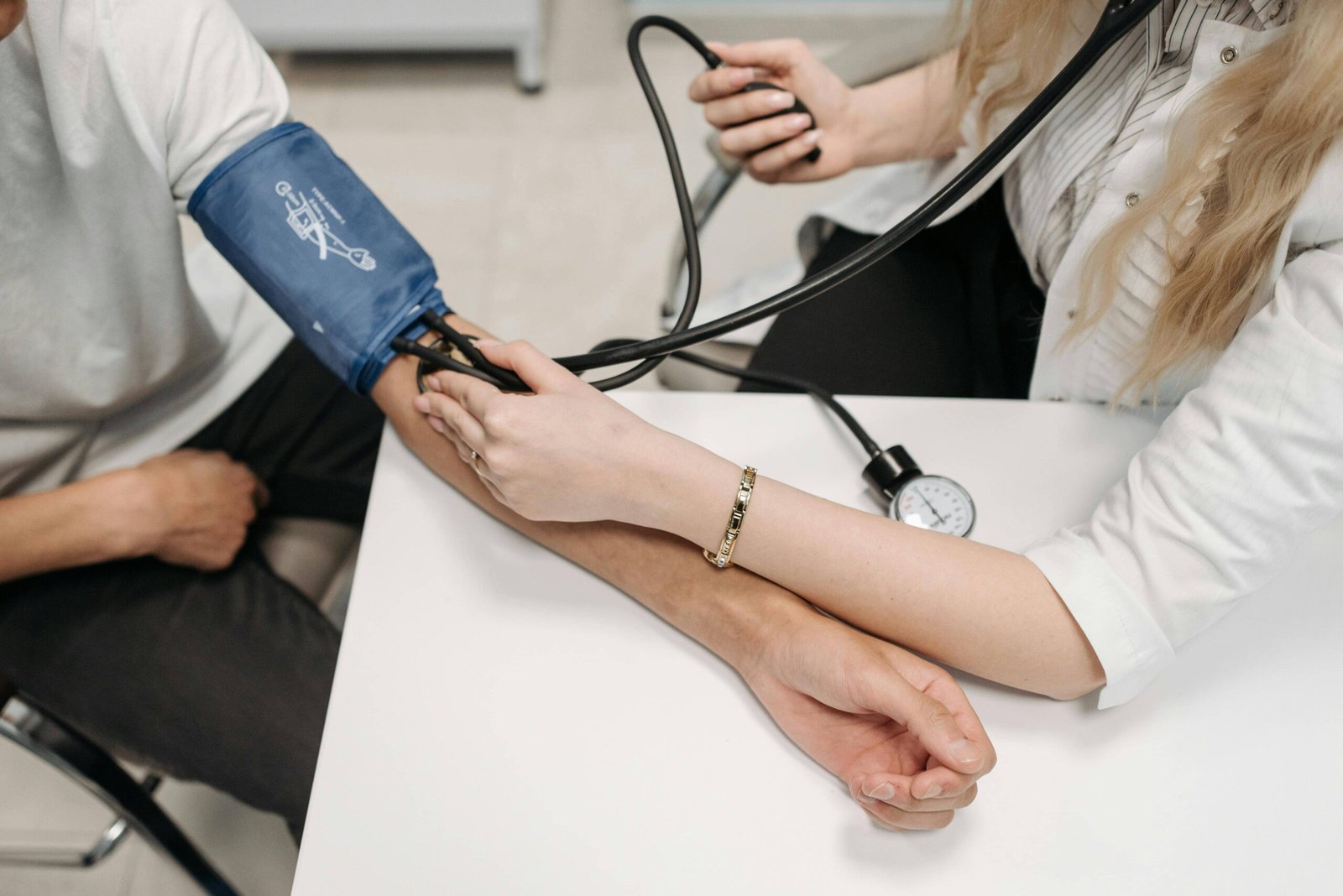 A healthcare professional checking a patient's blood pressure using a manual sphygmomanometer, emphasizing the importance of monitoring blood pressure and avoiding foods that contribute to high blood pressure.