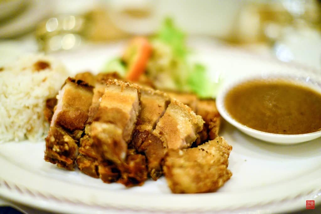 A plated meal featuring crispy breaded pork cut into bite-sized pieces, served with a side of steamed white rice, a small salad of mixed vegetables, and a bowl of savory brown gravy.