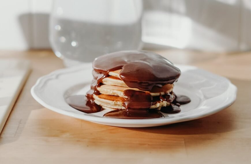A stack of pancakes covered in rich Milo Dalgona sauce on a white plate.