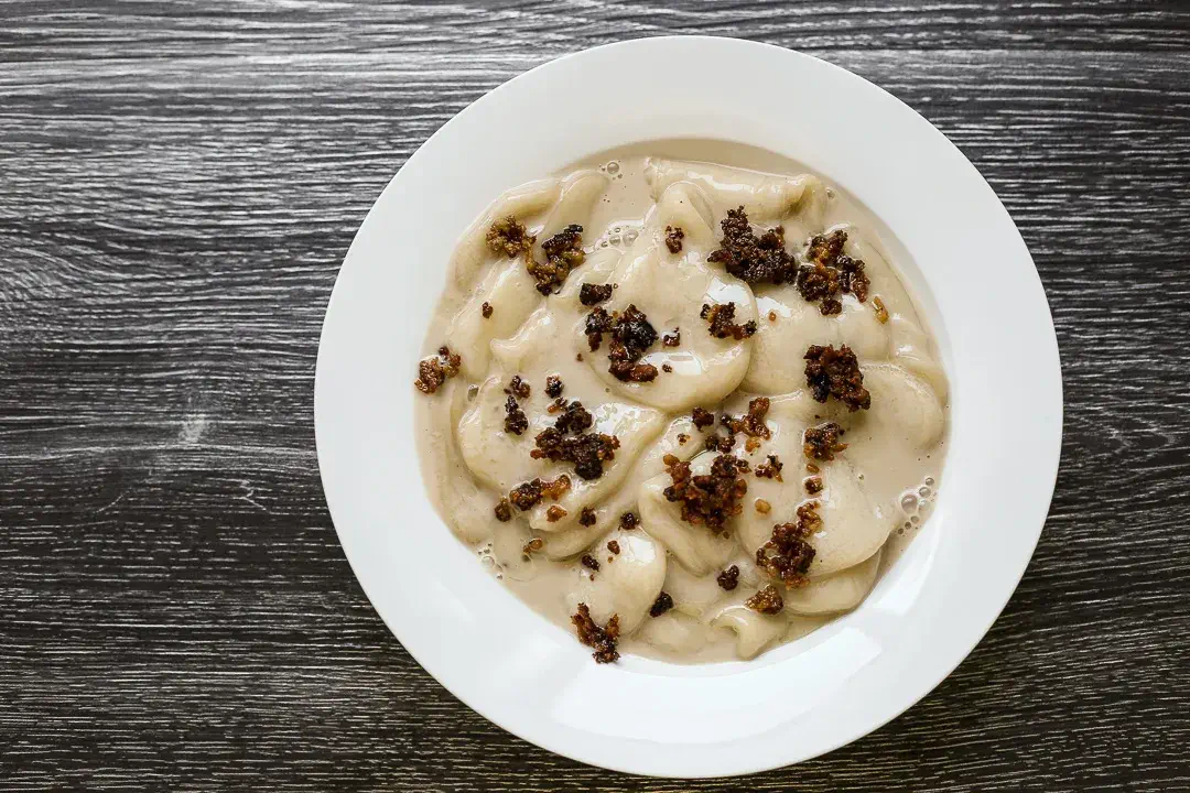 A plate of Palitaw, a traditional Filipino rice cake, served with a creamy coconut sauce and topped with crunchy toasted sesame seeds and sugar.