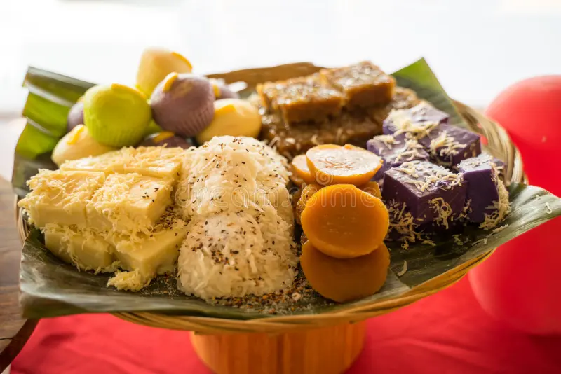 A beautifully arranged platter of traditional Filipino desserts, including palitaw sa latik, topped with shredded coconut and sesame seeds, alongside other colorful rice cakes and kakanin, perfect for showcasing a Palitaw Sa Latik recipe.