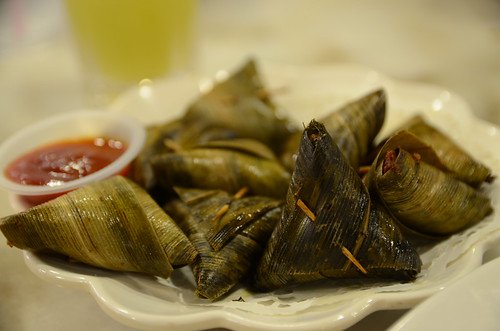 Grilled chicken wrapped in pandan leaves served with a side of dipping sauce.