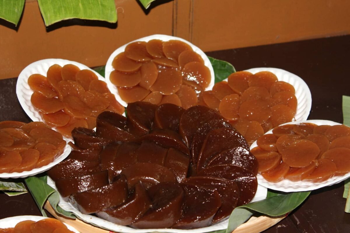 The image displays Pandan Kutsinta, a traditional Filipino rice cake made from glutinous rice flour and flavored with pandan. The brown, jelly-like rounds are arranged neatly on plates, showcasing their smooth, glossy texture. Typically served with grated coconut, these kutsinta are a favorite snack or dessert.