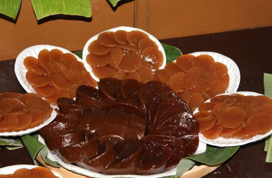 The image displays Pandan Kutsinta, a traditional Filipino rice cake made from glutinous rice flour and flavored with pandan. The brown, jelly-like rounds are arranged neatly on plates, showcasing their smooth, glossy texture. Typically served with grated coconut, these kutsinta are a favorite snack or dessert.