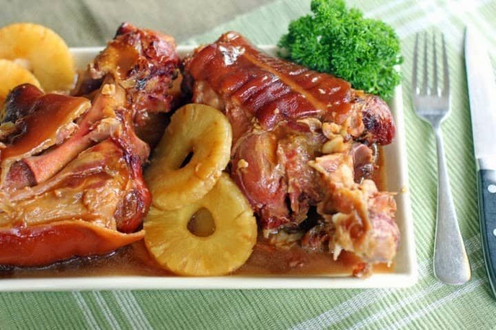 A plate of savory Pata Hamonado, featuring tender pork leg braised in a sweet pineapple sauce, garnished with pineapple rings and fresh parsley, highlighting a traditional Filipino Pata Hamonado recipe.