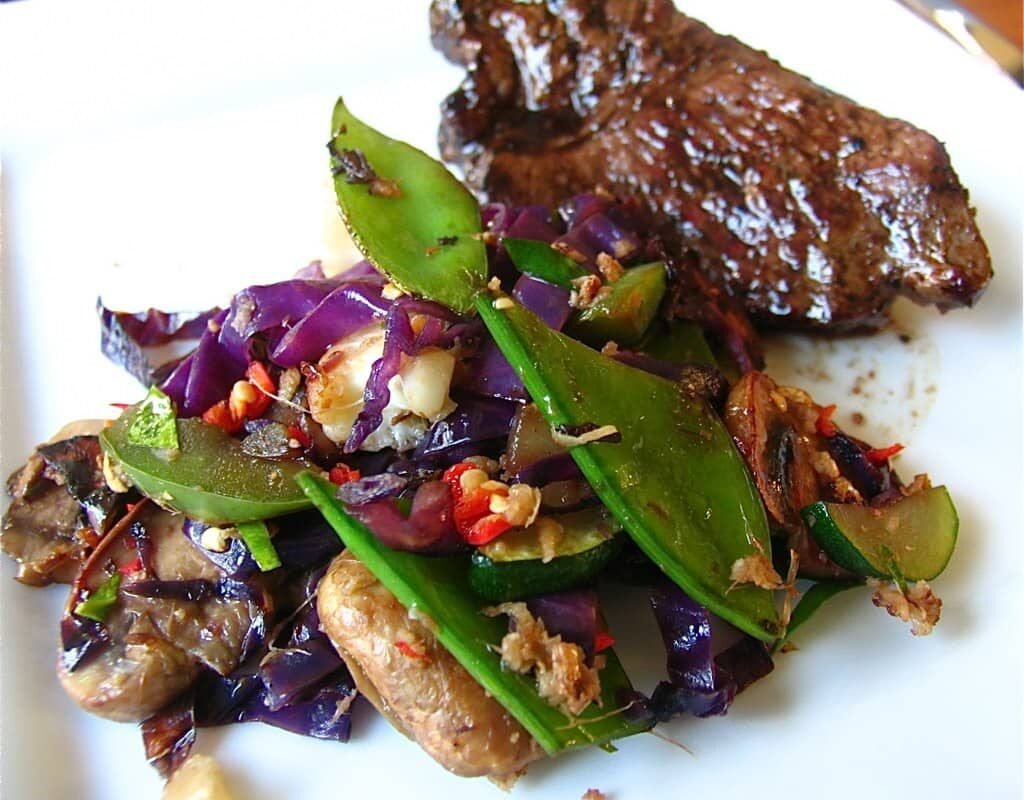 Pepper steak stir fry served with a colorful mix of vegetables on a white plate.