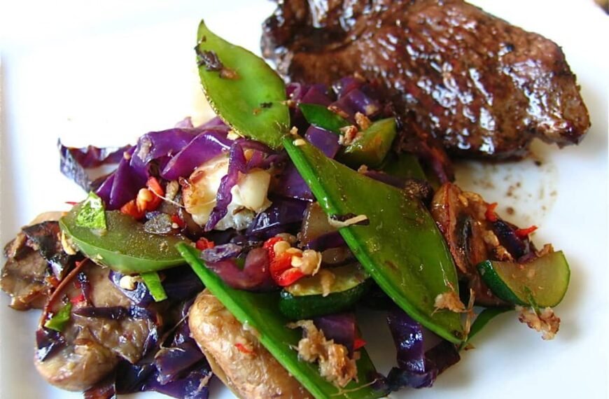 Pepper steak stir fry served with a colorful mix of vegetables on a white plate.