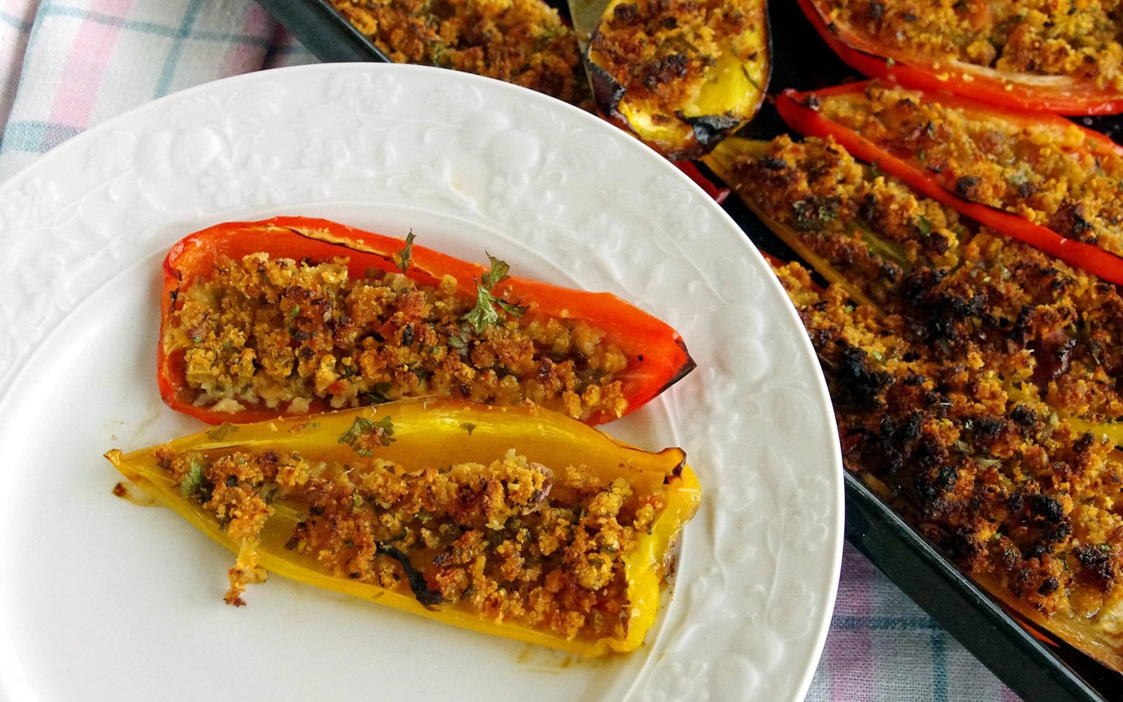 Stuffed bell peppers with a crumbly topping on a white plate.