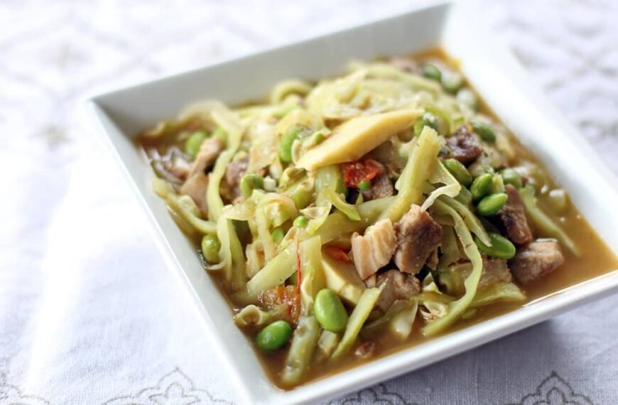 A vibrant bowl of Pinalatik Na Malunggay with Tulingan, showcasing a colorful medley of fresh malunggay leaves, tender slices of tulingan (mackerel), and savory vegetables. The dish is served in a light, flavorful broth, capturing the essence of Filipino home-cooked meals. The presentation highlights the hearty ingredients, including green beans and other fresh elements, in a white square dish.