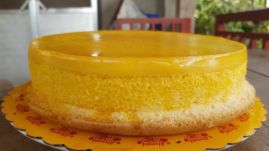 A close-up of a perfectly baked Puto Flan, also known as Leche Puto, featuring a golden-yellow custard layer on top of a soft and spongy puto base.