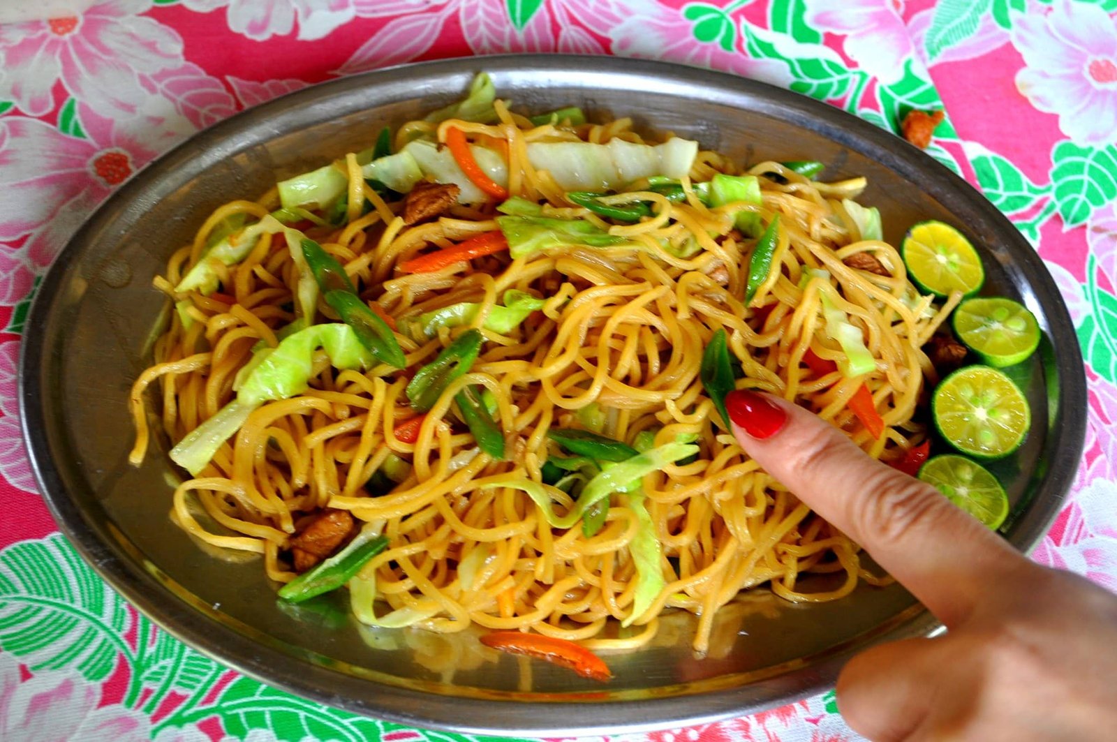 A vibrant plate of special pancit canton, stir-fried noodles with vegetables and lime on the side, served on a metal dish, showcasing a colorful and flavorful Filipino pancit canton recipe.