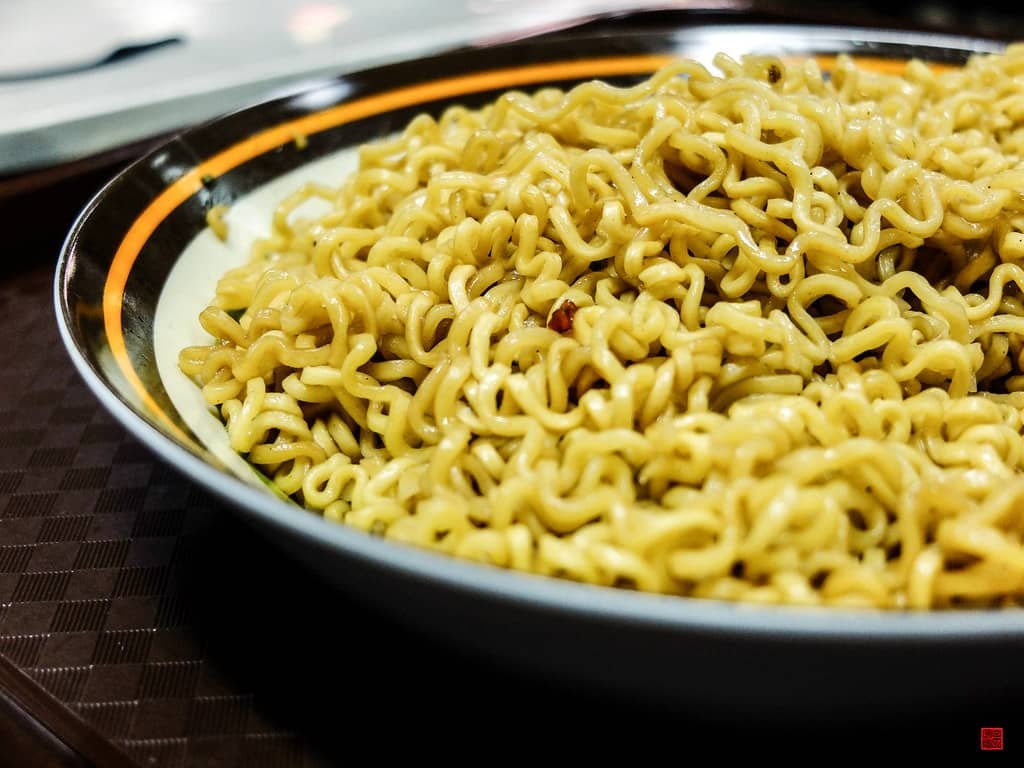 A close-up of a bowl of pancit canton, featuring thick stir-fried noodles with a light soy sauce glaze, perfect for an easy and delicious special pancit canton recipe.