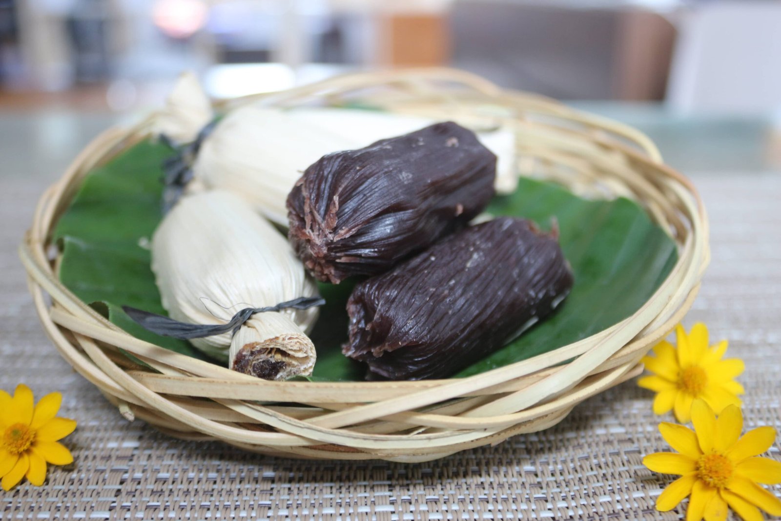 A basket containing traditional Suman Moron, a Filipino dessert made from glutinous rice mixed with cocoa and wrapped in banana leaves. The image highlights both the chocolate-flavored and regular variants, a delicious representation of the Suman Moron Chocolate Moron recipe.