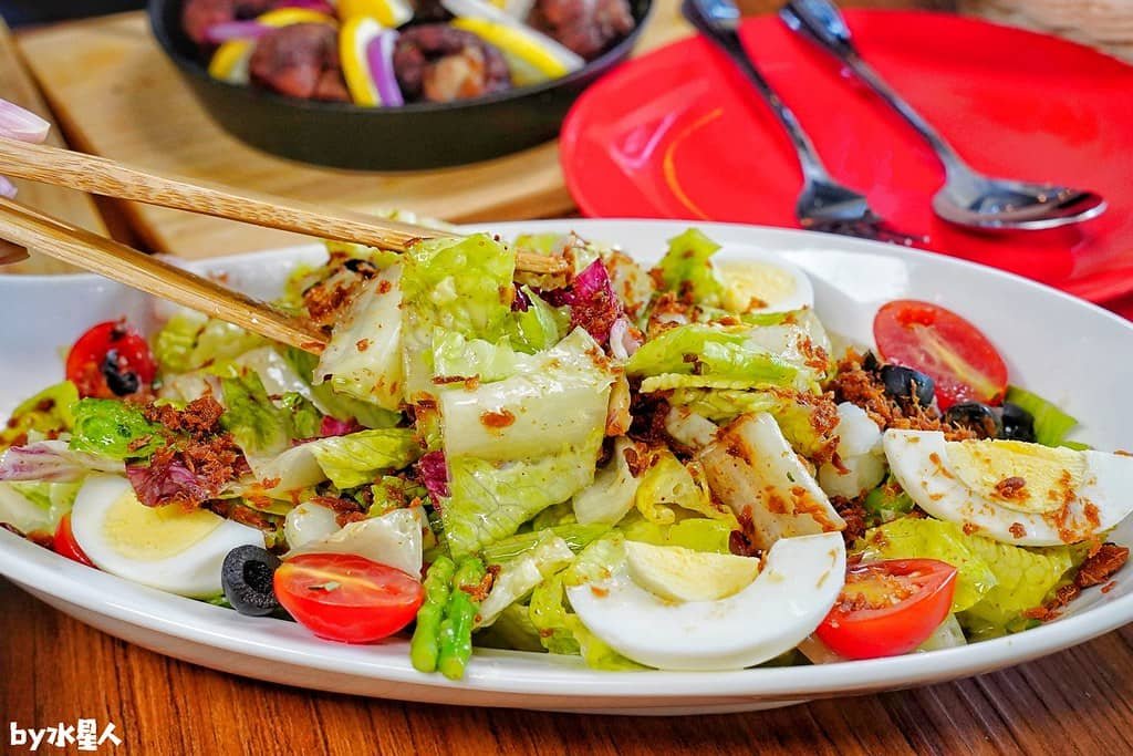 A vibrant vegetable salad, featuring fresh lettuce, cherry tomatoes, hard-boiled eggs, olives, and crispy toppings, served in a white dish with chopsticks, perfect for a healthy and delicious vegetable salad recipe.