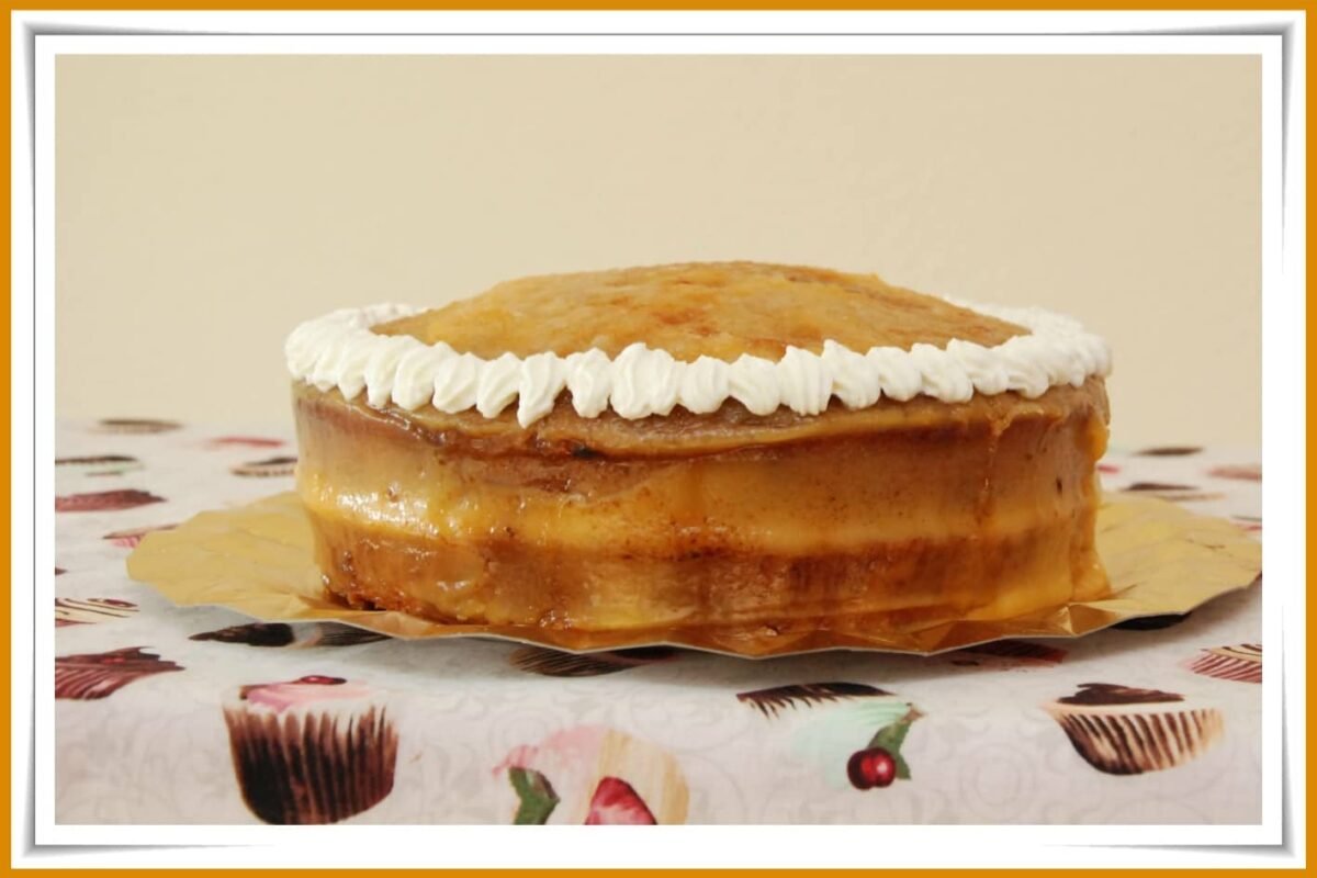 A creamy Yema cake topped with whipped frosting on a decorative tablecloth.