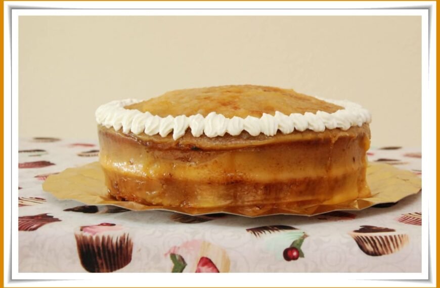 A creamy Yema cake topped with whipped frosting on a decorative tablecloth.
