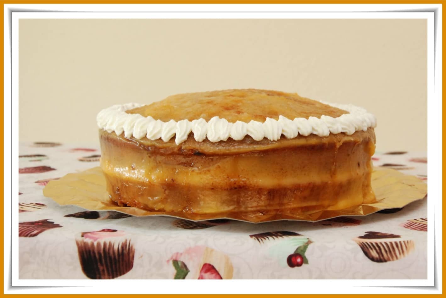 A creamy Yema cake topped with whipped frosting on a decorative tablecloth.